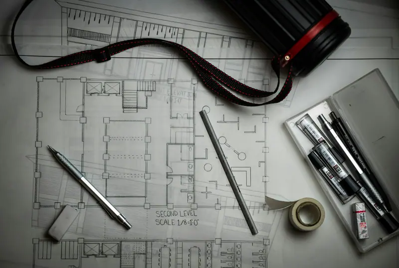 Architectural blueprints, pens and tools spread across a desk