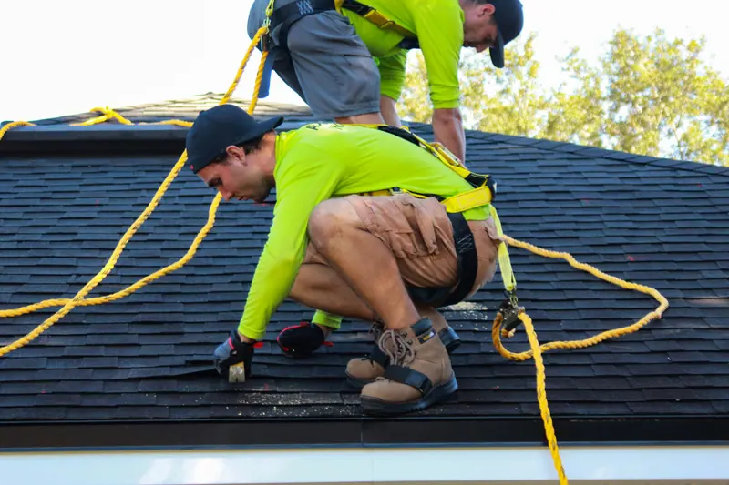 Roofer kneeling on a shingle roof while installing